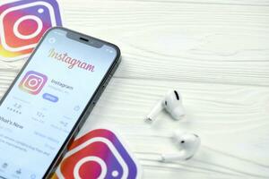 KHARKOV, UKRAINE - MARCH 5, 2021 Instagram icon and application from App store on iPhone 12 pro display screen with airpods pro on white table photo
