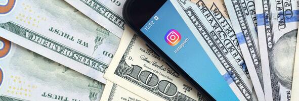 pantalla de teléfono inteligente con aplicación de instagram y muchos billetes de cien dólares. concepto de negocios y redes sociales foto