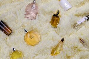kharkov, ucrania - 12 de enero de 2021 muchas botellas de perfume con nombres de marcas famosas se encuentran en una tela escocesa beige esponjosa foto