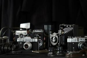 KHARKOV, UKRAINE - APRIL 27, 2021 Film photo cameras and another old retro photo equipment on black wooden table in photographer darkroom. Photographic gear from soviet union