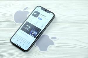KHARKOV, UKRAINE - MARCH 5, 2021 Apple TV icon and application from App store on iPhone 12 pro display screen on white table photo