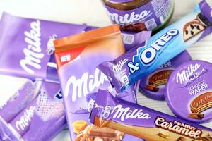 kharkov, ucrania - 2 de julio de 2021 productos de chocolate milka con diseño de envoltura de color lila clásico en mesa blanca foto