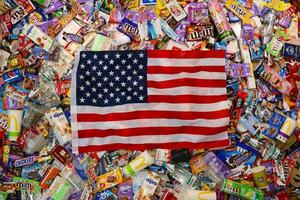KHARKOV, UKRAINE - AUGUST 10, 2021 US flag on big pile of various wrappings and empty disposable packages and cups from famous branded food production photo