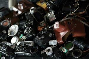 KHARKOV, UKRAINE - APRIL 27, 2021 Film photo cameras and another old retro photo equipment on black wooden table in photographer darkroom. Photographic gear from soviet union