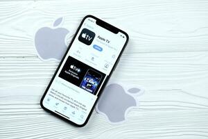 KHARKOV, UKRAINE - MARCH 5, 2021 Apple TV icon and application from App store on iPhone 12 pro display screen on white table photo