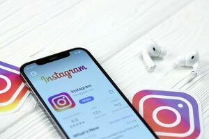 KHARKOV, UKRAINE - MARCH 5, 2021 Instagram icon and application from App store on iPhone 12 pro display screen with airpods pro on white table photo