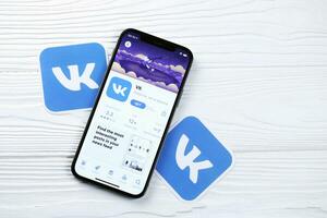 KHARKOV, UKRAINE - MARCH 5, 2021 VK icon and application from App store on iPhone 12 pro display screen on white table photo