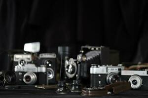 KHARKOV, UKRAINE - APRIL 27, 2021 Film photo cameras and another old retro photo equipment on black wooden table in photographer darkroom. Photographic gear from soviet union