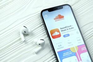 KHARKOV, UKRAINE - MARCH 5, 2021 Soundcloud icon and application from App store on iPhone 12 pro display screen with airpods pro on white table photo