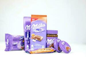 kharkov, ucrania - 2 de julio de 2021 productos de chocolate milka con diseño de envoltura de color lila clásico en mesa blanca foto