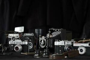 KHARKOV, UKRAINE - APRIL 27, 2021 Film photo cameras and another old retro photo equipment on black wooden table in photographer darkroom. Photographic gear from soviet union