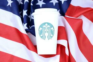 Jarkov, Ucrania - marzo 15, 2021 Starbucks taza en nosotros bandera. Starbucks sociedad es multinacional cadena de cafeterias con sede en Seattle, Washington foto