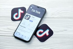 KHARKOV, UKRAINE - MARCH 5, 2021 Tiktok icon and application from App store on iPhone 12 pro display screen on white table photo