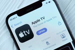 KHARKOV, UKRAINE - MARCH 5, 2021 Apple TV icon and application from App store on iPhone 12 pro display screen on white table photo