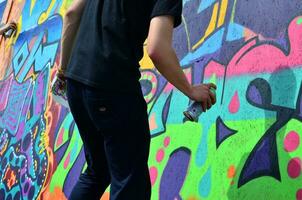 KHARKOV, UKRAINE - MAY 27, 2017 Festival of street arts. Young guys draw graffiti on portable wooden walls in the center of the city. The process of painting on walls with aerosol spray cans photo