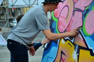 KHARKOV, UKRAINE - MAY 27, 2017 Festival of street arts. Young guys draw graffiti on portable wooden walls in the center of the city. The process of painting on walls with aerosol spray cans photo