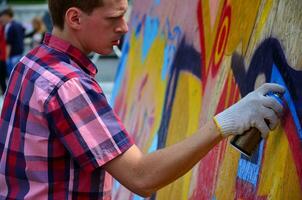 KHARKOV, UKRAINE - MAY 27, 2017 Festival of street arts. Young guys draw graffiti on portable wooden walls in the center of the city. The process of painting on walls with aerosol spray cans photo