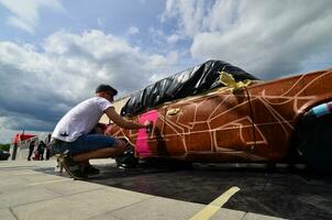 KHARKOV, UKRAINE - MAY 27, 2017 Festival of street art. Young guys draw graffiti on the car body in the city center. The process of drawing color graffiti on a car with aerosol cans photo