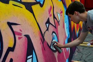 KHARKOV, UKRAINE - MAY 27, 2017 Festival of street arts. Young guys draw graffiti on portable wooden walls in the center of the city. The process of painting on walls with aerosol spray cans photo