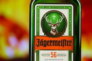 KYIV, UKRAINE - MAY 4, 2022 Jagermeister original alcohol bottle on wooden table with red fireplace photo