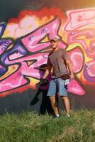 Young caucasian male graffiti artist drawing big street art painting in blue and pink tones photo