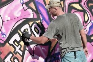 joven caucásico masculino pintada artista dibujo grande calle Arte pintura en azul y rosado tonos foto