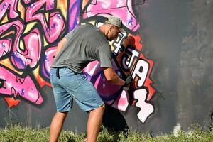 joven caucásico masculino pintada artista dibujo grande calle Arte pintura en azul y rosado tonos foto