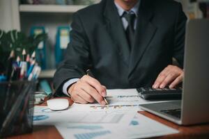 businessman working accountant document graph and chart on desk using calculator for calculate finance report in office. photo