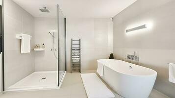 White ceramic bathtub placed near glass shower cabin in stylish spacious bathroom with heated towel rail and bright glowing lamps, Generative AI photo