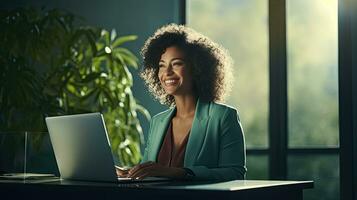 Smiling African American businesswoman sitting at table in her home office, reading documents and working using laptop photo