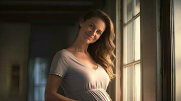 A pregnant woman stood smiling in the corner of the window with light streaming through the window. photo