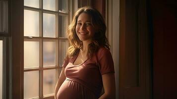 A pregnant woman stood smiling in the corner of the window with light streaming through the window. photo