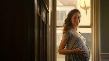 un embarazada mujer destacado sonriente en el esquina de el ventana con ligero transmisión mediante el ventana. foto