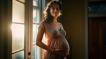 A pregnant woman stood smiling in the corner of the window with light streaming through the window. photo