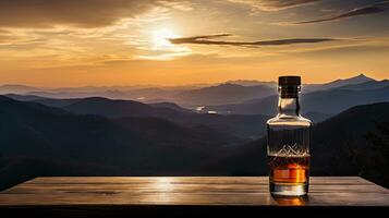 A whiskey glass and a bottle on a bar table In the background are mountains and a sea of mist at sunset. photo