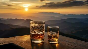 A whiskey glass and a bottle on a bar table In the background are mountains and a sea of mist at sunset. photo