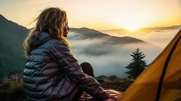 girl hiker in a tent and holding a cup mountains in the background photo