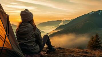 girl hiker in a tent and holding a cup mountains in the background photo