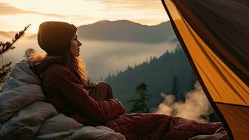 girl hiker in a tent and holding a cup mountains in the background photo