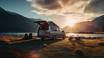 family camping car Go on holiday in a campervan, parked next to the river, with the mountains behind the sunset. photo
