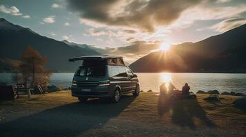 family camping car Go on holiday in a campervan, parked next to the river, with the mountains behind the sunset. photo