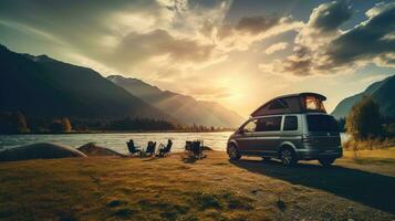 familia cámping coche Vamos en fiesta en un autocaravana, estacionado siguiente a el río, con el montañas detrás el puesta de sol. foto