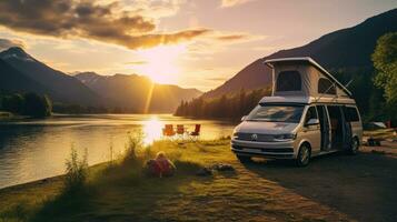 family camping car Go on holiday in a campervan, parked next to the river, with the mountains behind the sunset. photo