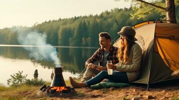 Young couple having a picnic sitting near a campfire and tent Drink coffee in the pine forest photo