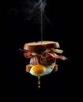 bacon sandwich hanging in the air with eggs and bread photo