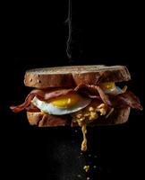 bacon sandwich hanging in the air with eggs and bread photo