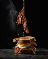 bacon sandwich hanging in the air with eggs and bread photo