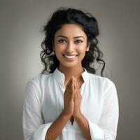 young woman in white cloths showing namaste hand gesture on dark background generative AI photo