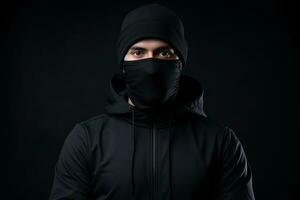 a man wearing a black hoodie and a black face mask photo