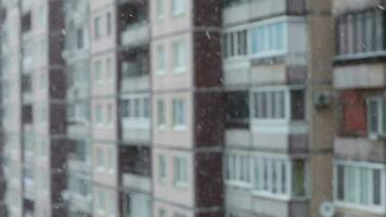 nevada en el ciudad, copos de nieve que cae en contra el antecedentes de el ventanas de el casa video